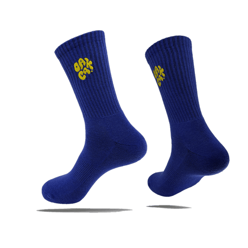 Side view of a pair of blue crew socks with a yellow embroidered OAK CA blob-style wordmark on the side calves.