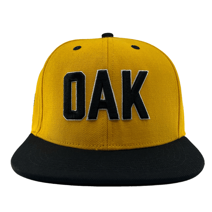 Front view of a yellow hat with a black flat bill, black embroidered details, and embroidered OAK block text on the front crown.