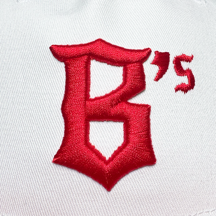 A close-up of white fabric on the Oakland Ballers 5 Panel Cap, featuring a large red gothic "B," a small red apostrophe, and the number "5," reflecting Oakland Ballers' signature style.