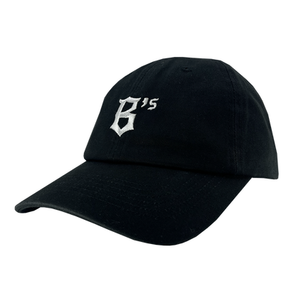 The Oakland Ballers Dad Hat is a black baseball cap with a curved brim. On the front, it showcases a white embroidered design featuring a stylized letter "B" and the number "15" slightly above and to the right, symbolizing the Oakland Ballers. Its simple and clean design makes it perfect for fans of this community-focused experience.