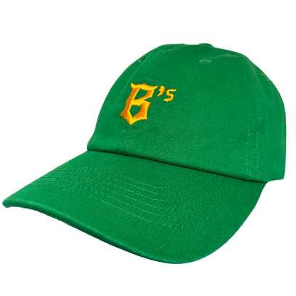 The Oakland Ballers Dad Hat by Oakland Ballers is a green cap with a yellow embroidered “B’s” on the front, inspired by the pro baseball team. It features a curved brim, visible stitching, and is shown against a plain white background.