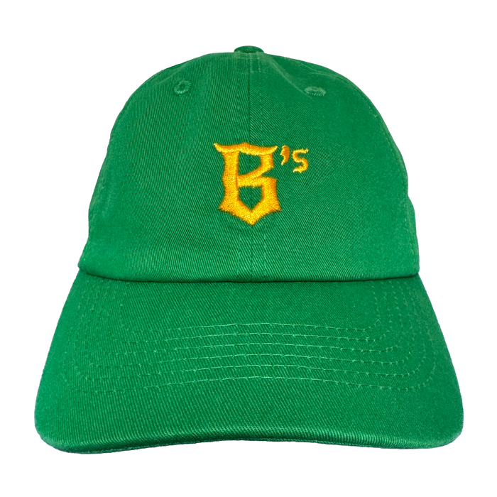 The Oakland Ballers Dad Hat features a green design with a yellow embroidered "B's" on the front, visible stitching, and a curved brim. The cap is photographed against a plain white background. Brand: Oakland Ballers.