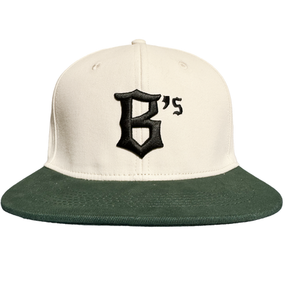 Introducing the Oakland Peloteros Hat by Oakland Ballers—a cream-colored baseball cap with a dark green brim, inspired by the Oakland Ballers from the Pioneer League. The front displays a bold black "B's" in gothic font, capturing the vibrant spirit of Oakland’s newest baseball team. Set against a plain white background.