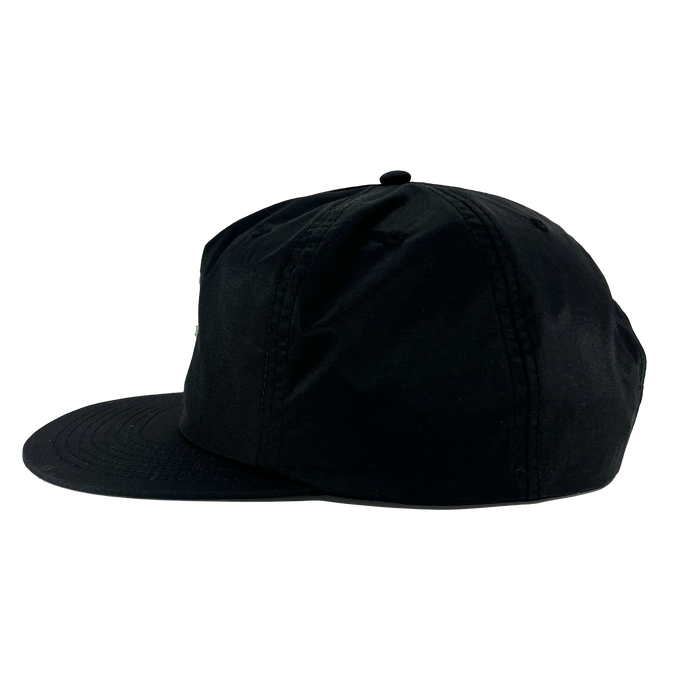 A side view of the Oakland Soul Surf Cap is depicted against a white background. This black cap features a flat brim and a structured crown, complemented by a button on top and stitch detailing along the seams and brim. Reflecting the dynamic spirit of Oakland Soul in the USL W-League, the cap appears plain with no visible logos or designs.