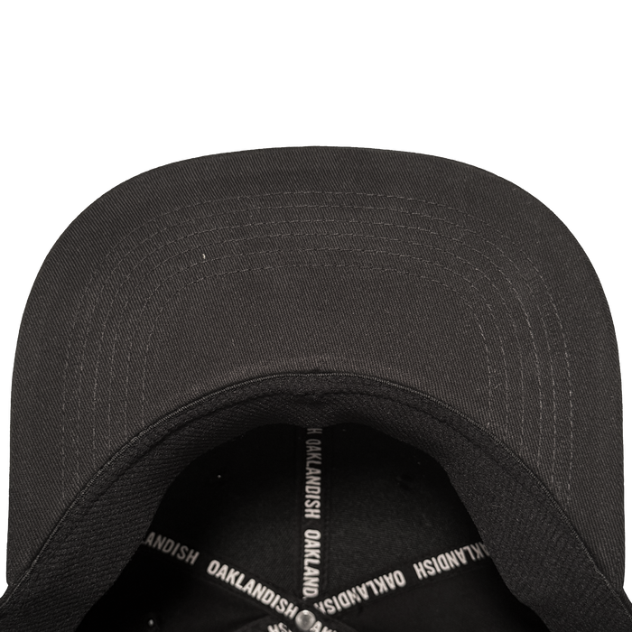 A close-up, top-down view of the Oakland Stand Up Hat by Oakland Ballers, showing its curved-brim black cap, visible stitching, and interior sweatband with crossed bands reading "OAKLANDISH," honoring Oakland’s baseball team spirit.