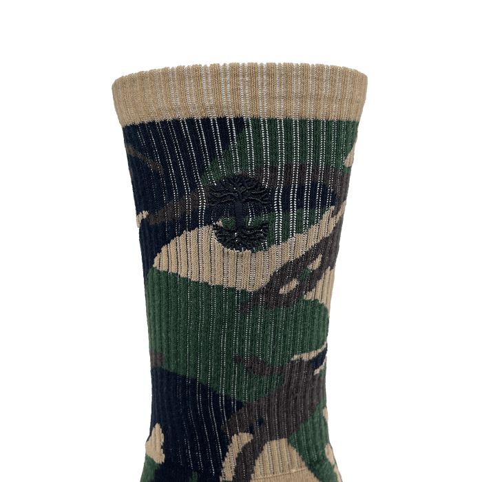Close-up of embroidered small black Oaklandish tree logo on the side of camo crew sock.