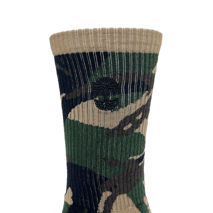 Close-up of embroidered small black Oaklandish tree logo on the side of camo crew sock.