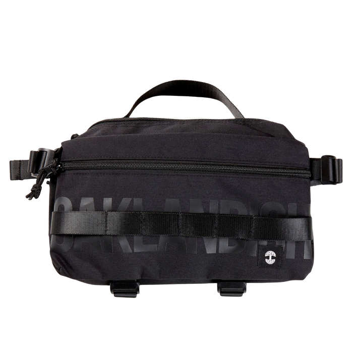 A black nylon hip bag with a black Oaklandish wordmark, front zipper, top handle, waist belt, & small white Oaklandish tree logo.