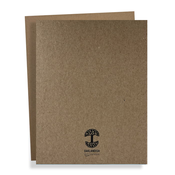 Two brown cardboard folders are stacked, with the one in front slightly overlapping the one at the back. The front folder, known as the Oaklandish New Logo Card by Never Elsewhere, is crafted from recycled brown kraft paper and features a black logo of a tree with roots along with the text "OAKLANDISH" underneath. The overall design is simple and minimalistic.