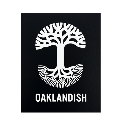 A black background showcases a striking white graphic of a tree creatively designed to resemble the letter "T," with the top half depicting branches and the bottom half depicting roots. Below this symbolic tree, "OAKLANDISH" is prominently featured in uppercase letters on a silver foil cardstock print, known as the Oaklandish New Logo Print by Never Elsewhere.