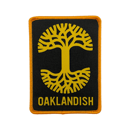 Black woven iron-on patch with gold Oaklandish tree logo and wordmark.