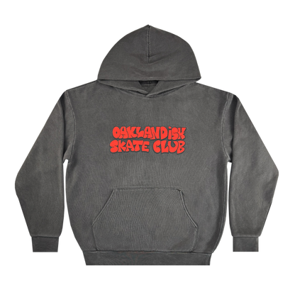 The Oaklandish Skate Club Hoodie by Oaklandish is a charcoal-grey pullover with a front pocket and hood. "OAKLANDISH SKATE CLUB" in bold, wavy red letters decorates the chest. The hoodie is shown laid flat on a white background.