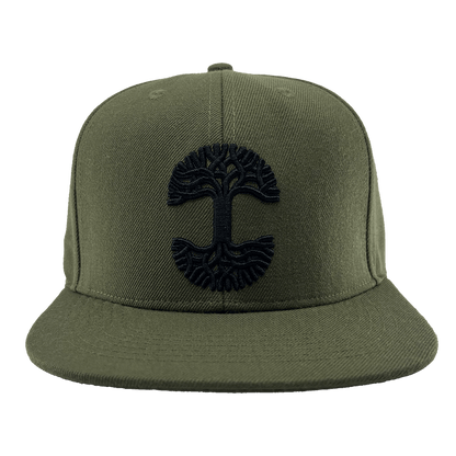 Front view of the Old English Aft Snapback by Oaklandish, an olive green hat featuring a black embroidered stylized tree with large roots and branches. The adjustable snapback cap has a flat brim, six-panel construction with stitched eyelets, and a button on top.