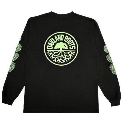 The ORSC Ryujin LS Tee by Oakland Roots SC is a black long-sleeve shirt with a large circular light green "Oakland Roots" tree logo on the back and repeating light green Roots SC tree graphics down both sleeves. Laid flat on a white background.