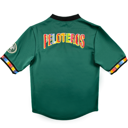 The Peloteros Jersey by Oakland Ballers features a vibrant green design, showcased from the back with “PELOTEROS” boldly displayed in rainbow-colored letters—a tribute to the team’s lively spirit. Multicolored stripes accent the sleeve cuffs, accompanied by a circular patch on the left sleeve that honors their Pioneer League heritage. The black collar stands out against a plain white background.