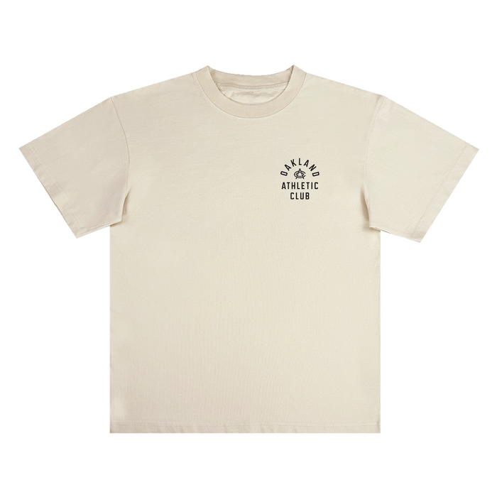 The Prestigious Tee by OAC is a classic fit, heavy-weight cotton t-shirt in plain off-white. It features “OAKLAND ATHLETIC CLUB” printed in black alongside a small laurel wreath graphic on the left chest. The shirt is displayed flat against a white background.