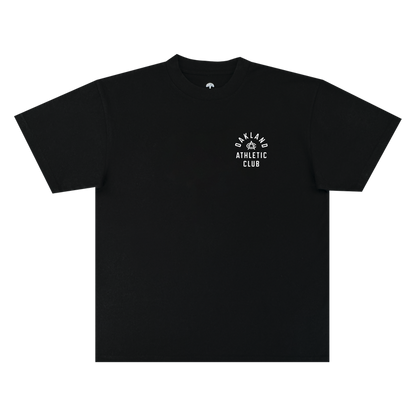 The OAC Prestigious Tee is a black, short-sleeve classic fit t-shirt featuring “OAKLAND ATHLETIC CLUB” printed in a curved and stacked white font on the left chest, with a small graphic above the text. Made from heavy-weight cotton, it is photographed against a plain white background.