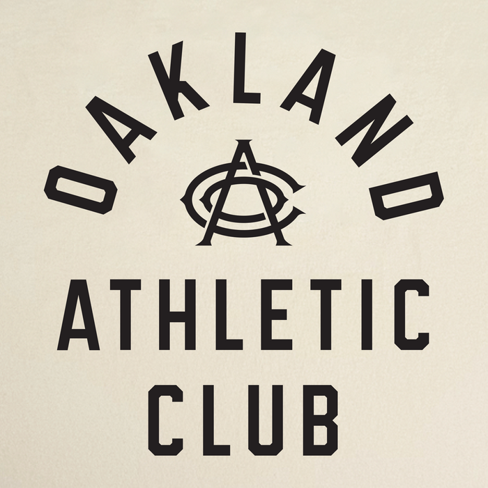 Text reads “OAKLAND ATHLETIC CLUB” in bold black letters, with “OAKLAND” arched above a stylized overlapping “OAC” monogram and “ATHLETIC CLUB” stacked below. This design appears on the OAC Prestigious Tee—a classic fit t-shirt crafted from soft, heavyweight cotton. The background is a light beige.