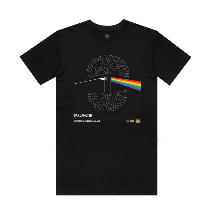 The Prismatic Tee by Oaklandish is a men’s black 100% cotton shirt with a white stylized tree and rainbow beam inspired by Pink Floyd. It reads “OAKLANDISH,” has rainbow stripes, and says: “EVERYONE BELONGS IN OAKLAND. EST. 2000.”.
