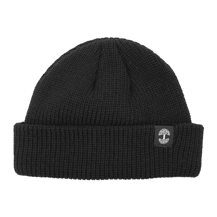The Ramos Beanie by Oaklandish is a black knit beanie featuring a folded cuff. The cuff showcases an embroidered logo of a white tree inside a gray circular border. Made from woven acrylic, the knit pattern's texture is clearly visible, contributing to its cozy and warm appearance.