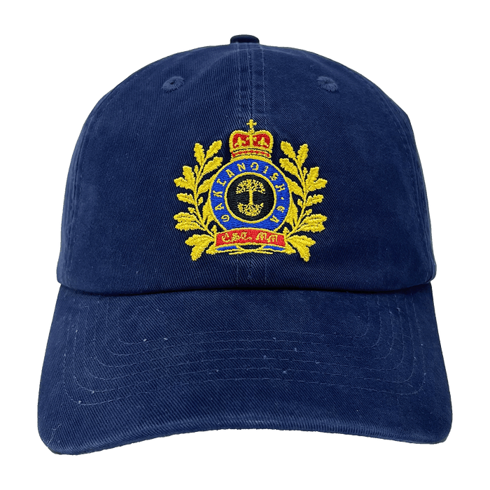 The Regal Crest Dad Hat by Oaklandish is a navy blue hat featuring an embroidered gold emblem on the front. The intricate design includes a crown at the top, gold laurel wreaths on either side, and a central shield with detailed symbols. Blue text is threaded within the emblem, framed by the wreaths. Made from 100% cotton, it also includes an adjustable strap for added comfort.