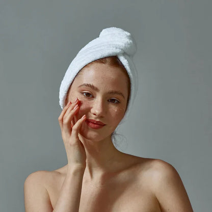white woman white hair towel applying facial serums dermal essentials skincare
