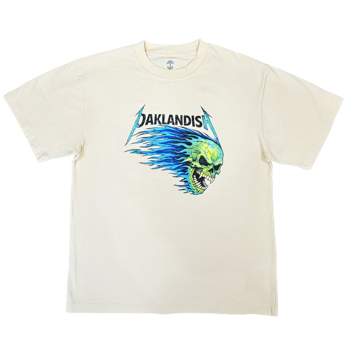Introducing the Sandman Tee by Oaklandish: a men’s cotton t-shirt in cream, featuring “OAKLANDISH” in black, stylized lettering above a bold green flaming skull graphic with blue flames extending behind it, all centered on the chest. This classic fit tee comes with short sleeves and a simple crew neckline.
