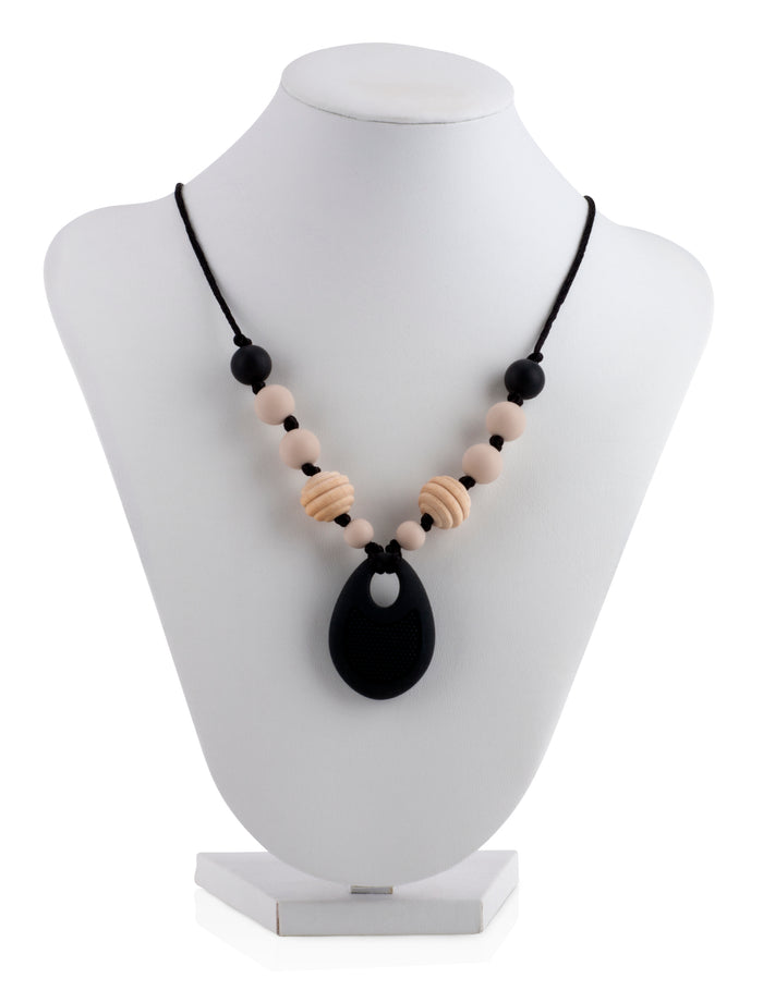 The Nuby Silicone Teething Necklace features black and beige beads with a large black pendant, shown on a white jewelry bust against a white background.