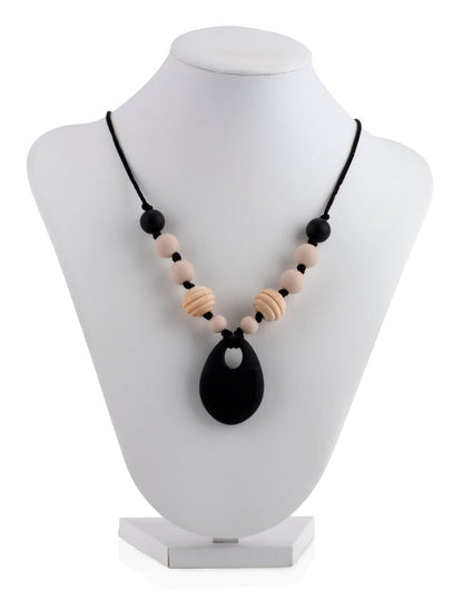 The Nuby Silicone Teething Necklace features black and beige beads with a large black pendant, shown on a white jewelry bust against a white background.