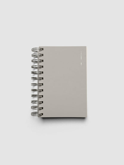 Spiral Notebook in size CP Petite and color Ash with Lined Notes interior pages shown closed displaying the soft touch dashboard.