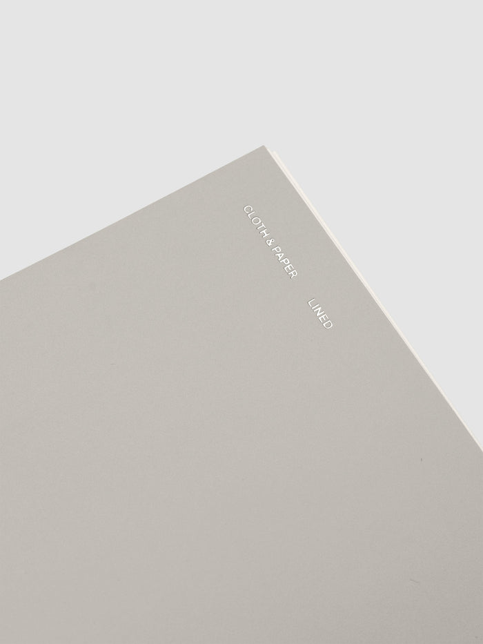 Spiral Notebook in size CP Petite and color Ash with Lined Notes interior pages showing a close up of the foil details on the soft touch dashboard.