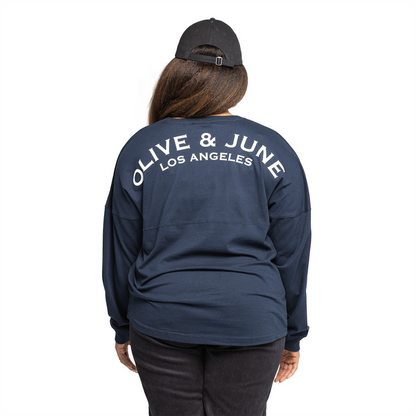 Back view of a navy Summer Sailor Long Sleeve Shirt with white Olive and June Los Angeles lettering worn with black cap