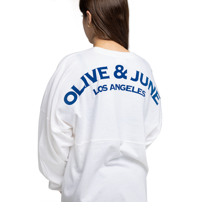 Back view of white Summer Sailor Long Sleeve Shirt with bold navy Olive & June Los Angeles lettering worn by model