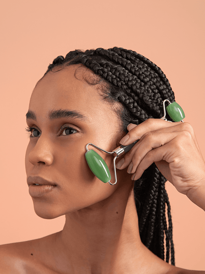 Model using jade facial roller to smooth out fascia on cheeks