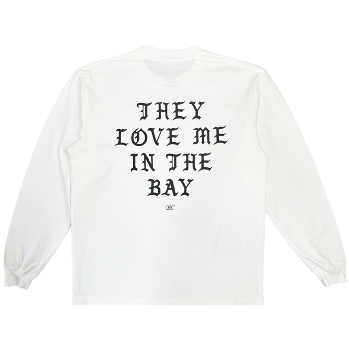 A heavyweight cotton long sleeve t-shirt, the They Love Me LS Tee By Doc from By DOC features a white base with bold black Gothic text reading “THEY LOVE ME IN THE BAY” across the back and a small logo underneath. Designed in men’s sizing, this shirt includes ribbed cuffs and a classic crew neckline.