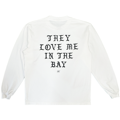 A heavyweight cotton long sleeve t-shirt, the They Love Me LS Tee By Doc from By DOC features a white base with bold black Gothic text reading “THEY LOVE ME IN THE BAY” across the back and a small logo underneath. Designed in men’s sizing, this shirt includes ribbed cuffs and a classic crew neckline.