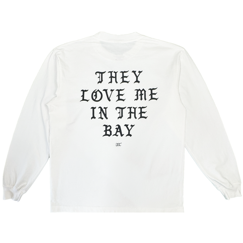 A heavyweight cotton long sleeve t-shirt, the They Love Me LS Tee By Doc from By DOC features a white base with bold black Gothic text reading “THEY LOVE ME IN THE BAY” across the back and a small logo underneath. Designed in men’s sizing, this shirt includes ribbed cuffs and a classic crew neckline.