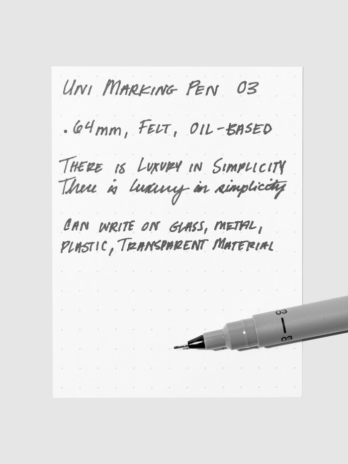Uni Pin Marking Pen, 03, Cloth and Paper. Pen resting on paper displaying writing sample.