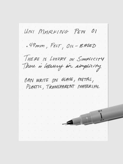 Uni Pin Marking Pen, 01, Cloth and Paper. Pen resting on paper displaying writing sample.