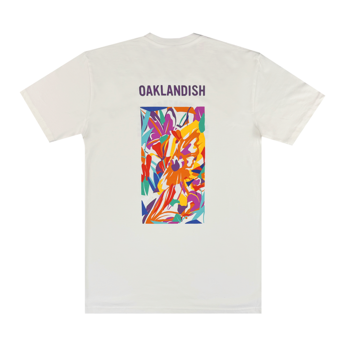 The Urban Tropics Tee by Oaklandish features bold purple "OAKLANDISH" text on the upper back and a vibrant floral design by Oakland artist Kalani Ware in a central rectangular panel.