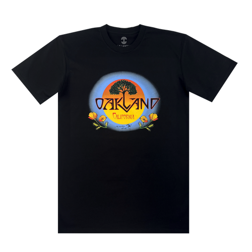 The Oaklandish Vanguard Tee features a classic fit and a Stanley Mouse-inspired graphic: a large tree silhouetted against an orange and blue sunset, with “OAKLAND” above “California” on a yellow banner, plus orange poppies and green leaves.