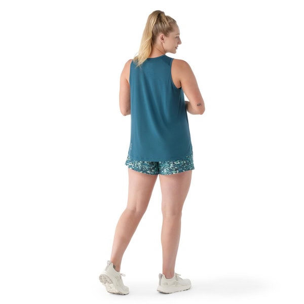 Woman wearing a teal tank top and patterned shorts on a white background