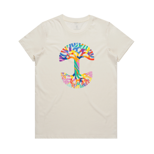 The Women's Urban Tropics Tee by Oaklandish is a cream-colored shirt with a bold abstract "T" on the chest, showcasing Kalani Ware’s vibrant multicultural design in blue, orange, yellow, green, pink, and purple hues.