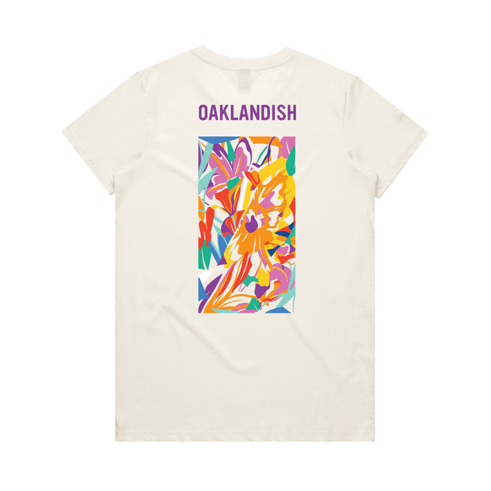 The Women's Urban Tropics Tee by Oaklandish features a cream color, “OAKLANDISH” in purple, and Kalani Ware’s vibrant abstract art with swirling yellow, orange, red, purple, pink, and blue shapes centered on the back.