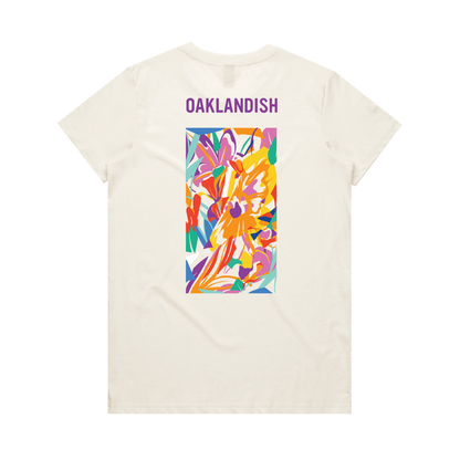 The Women's Urban Tropics Tee by Oaklandish features a cream color, “OAKLANDISH” in purple, and Kalani Ware’s vibrant abstract art with swirling yellow, orange, red, purple, pink, and blue shapes centered on the back.
